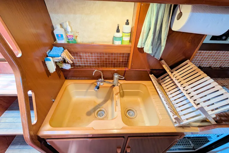 Iteration Yacht Photos Pics Kitchen sink area on a 1994 Amel 53 Super Maramu yacht with cleaning supplies.