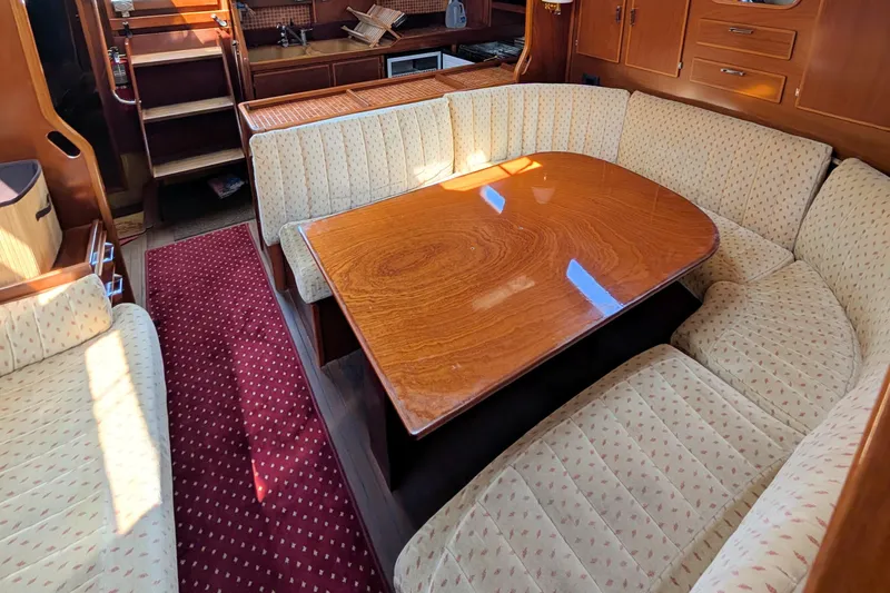 Iteration Yacht Photos Pics Interior of 1994 Amel 53 Super Maramu yacht with wooden table and cushioned seating.