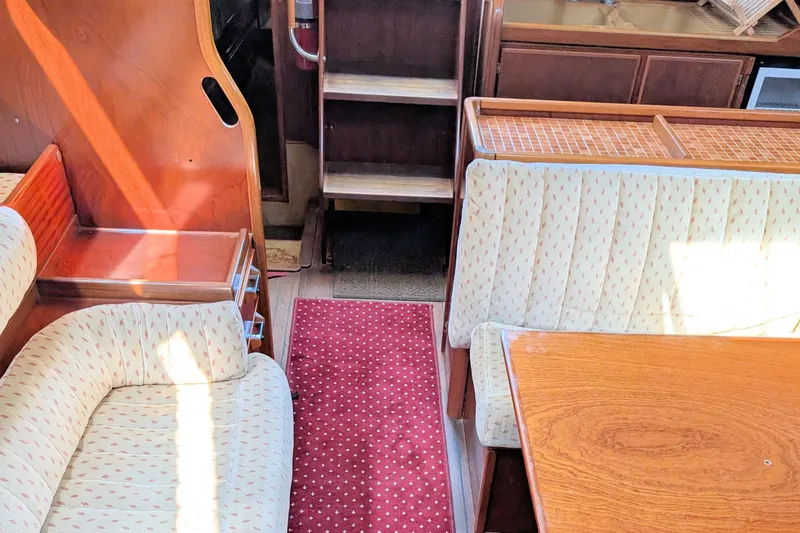 Iteration Yacht Photos Pics Interior of 1994 Amel 53 Super Maramu yacht with wooden table and patterned seating.