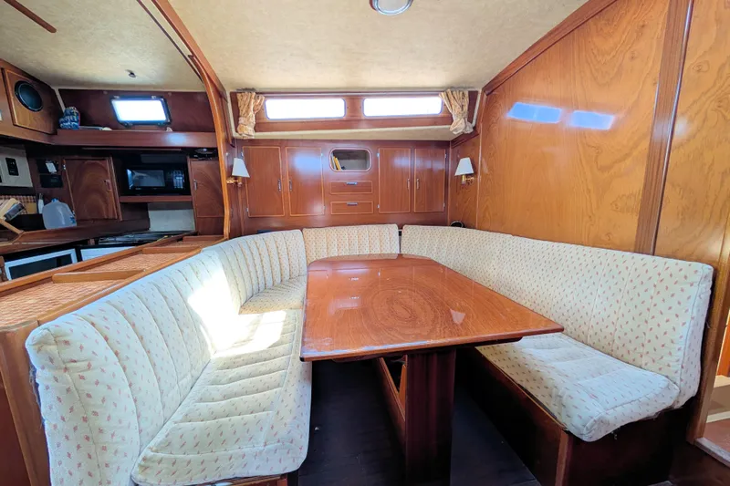 Iteration Yacht Photos Pics Interior of 1994 Amel 53 Super Maramu yacht with cozy dining area and wooden finishes.