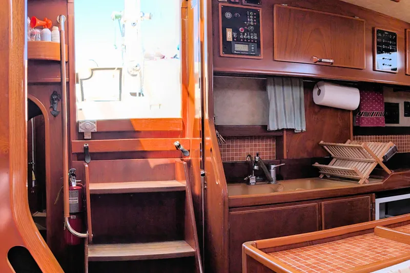 Iteration Yacht Photos Pics Interior of 1994 Amel 53 Super Maramu yacht, featuring a wooden kitchen and staircase.