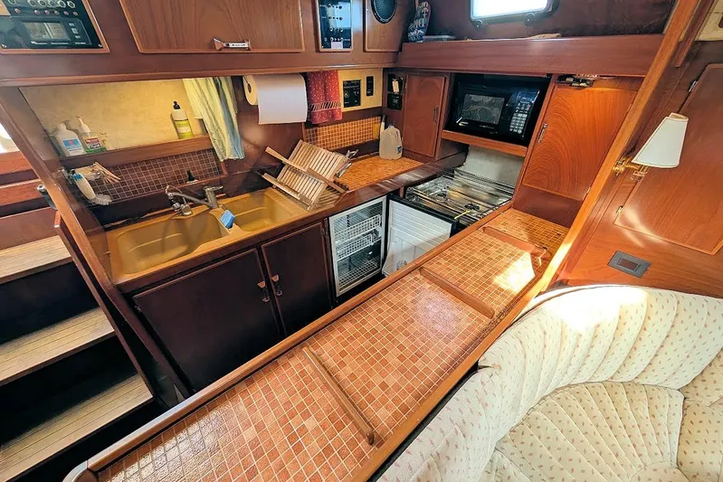 Iteration Yacht Photos Pics Interior of 1998 Amel 53 Super Maramu yacht kitchen with wooden cabinetry and appliances.