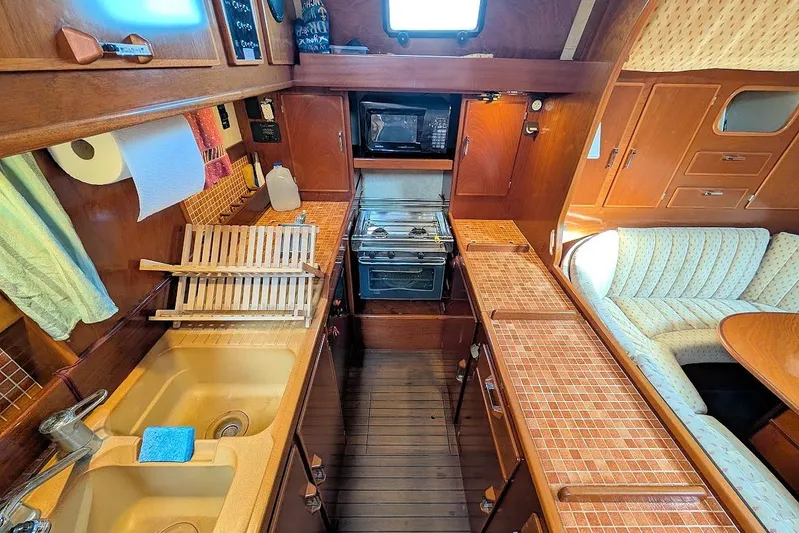 Iteration Yacht Photos Pics Interior of 1998 Amel 53 Super Maramu yacht kitchen with wooden cabinetry and appliances.