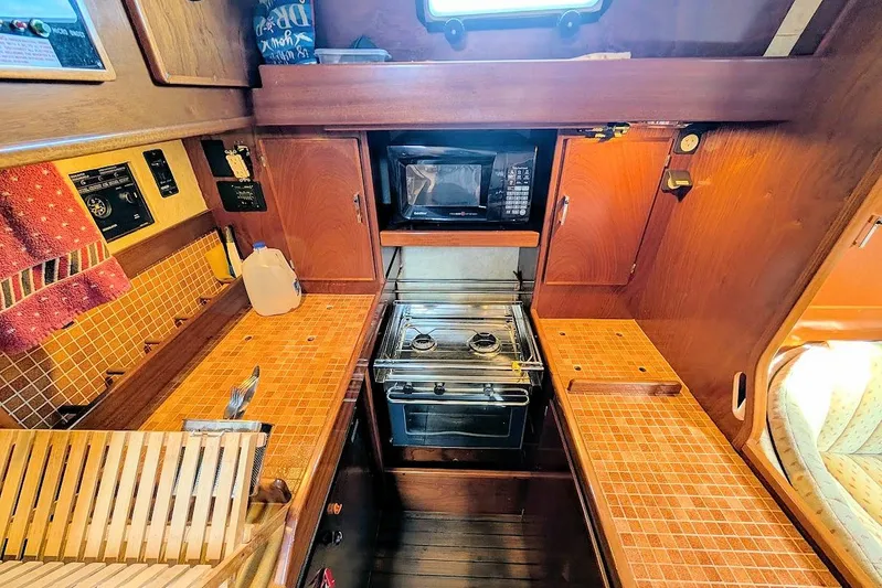 Iteration Yacht Photos Pics 1998 Amel 53 Super Maramu yacht kitchen with stove, microwave, and wooden cabinetry.