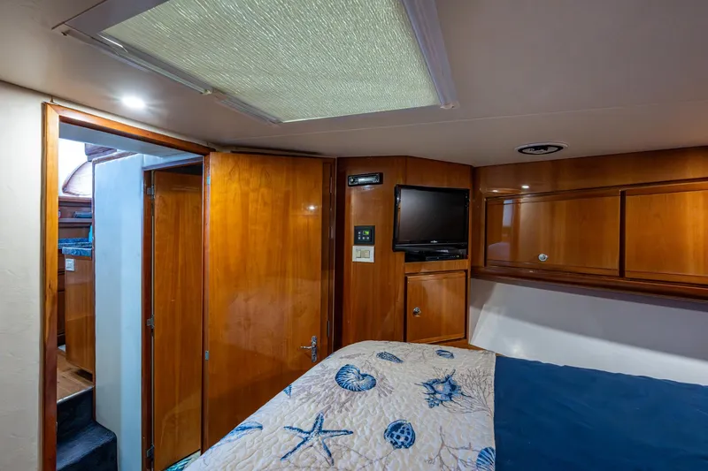 Vet Billz Yacht Photos Pics Interior of 2001 Bertram 390 yacht cabin with wood paneling and nautical-themed bedding.