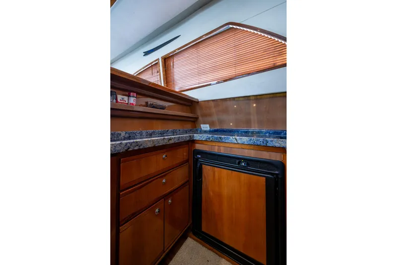 Vet Billz Yacht Photos Pics Interior of 2001 Bertram 390 yacht kitchen with wooden cabinets and blue countertop.