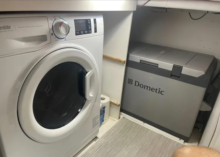  Yacht Photos Pics Laundry area with a washing machine and a Dometic cooler in a compact space.