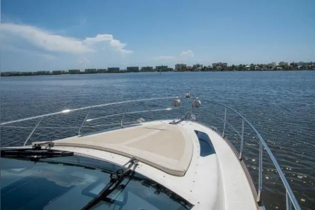Why Knot Yacht Photos Pics 2011 Marquis Sport Coupe cruising on a calm, scenic waterway under a clear blue sky.