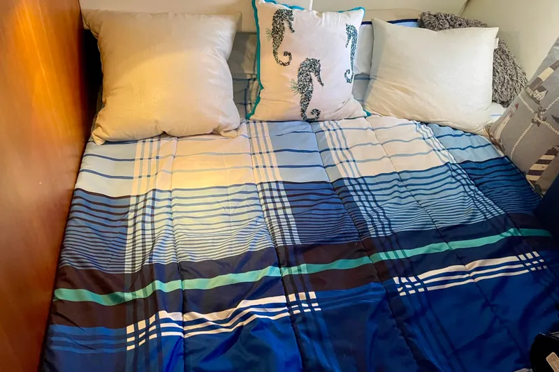 Yacht Photos Pics Cozy bed with blue plaid bedding and seahorse-themed pillows on a 2003 Silverton 38 Convertible.