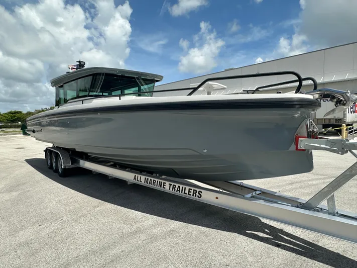  Yacht Photos Pics 2020 Axopar 37 XC CROSS CABIN boat on trailer under a cloudy sky.