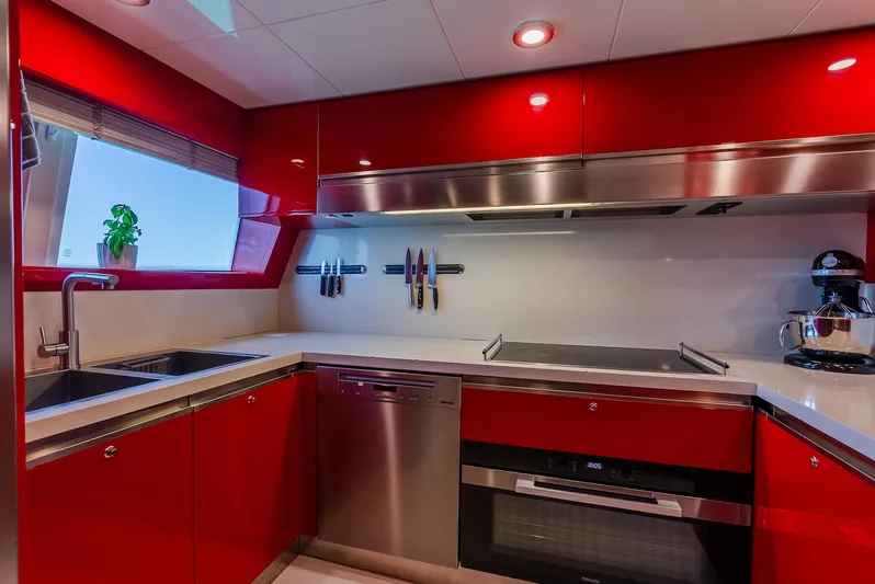 One And Only Yacht Photos Pics Modern kitchen with red cabinets, stainless steel appliances, and a window view. Custom Line 100, 2012.