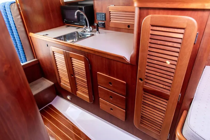 Chaser Yacht Photos Pics 2004 Hinckley Picnic Boat EP interior with wooden cabinetry and compact kitchen area.