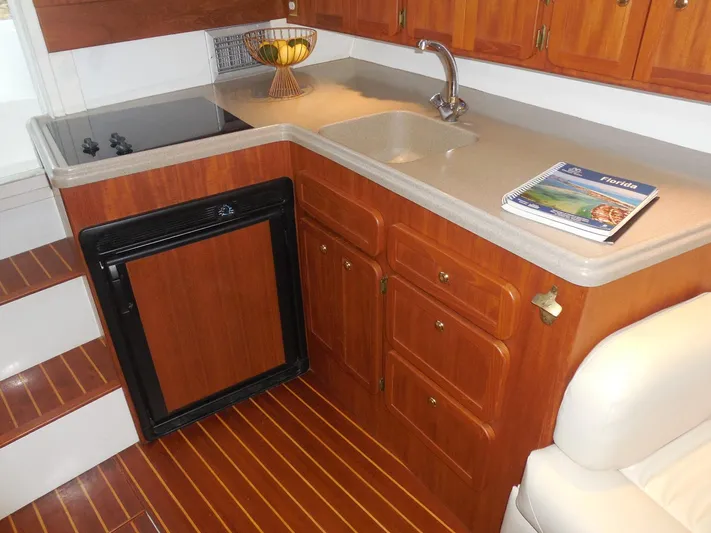 Yacht Photos Pics 2005 Stamas 370 Express yacht kitchen with wooden cabinets, sink, and compact fridge.