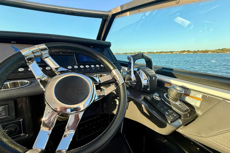  Yacht Photos Pics 2022 Monterey 385SS Super Sport boat dashboard with steering wheel and controls, overlooking water.