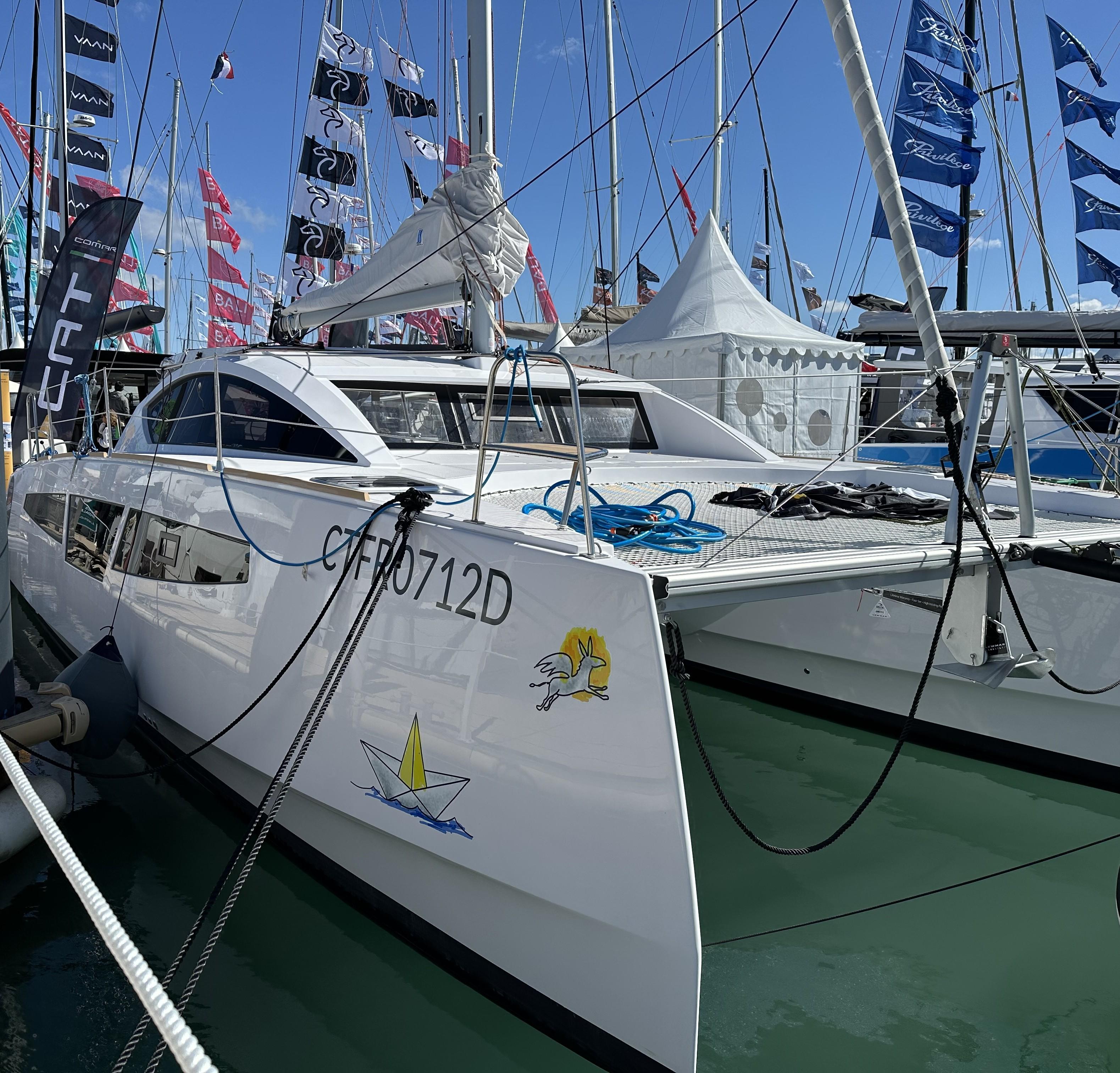 2025 Comar C-Cat 38 Catamaran docked at a marina, surrounded by flags and tents.