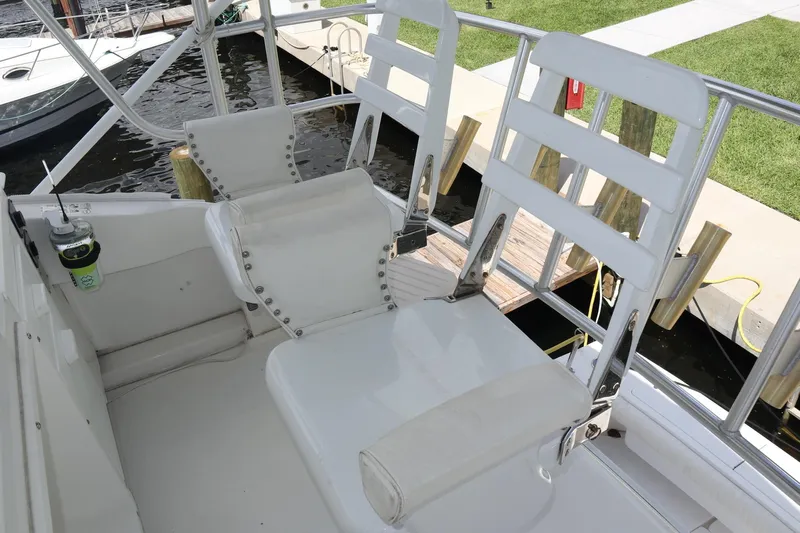  Yacht Photos Pics 2005 Luhrs 38 Convertible boat seating area with white chairs and dock view.