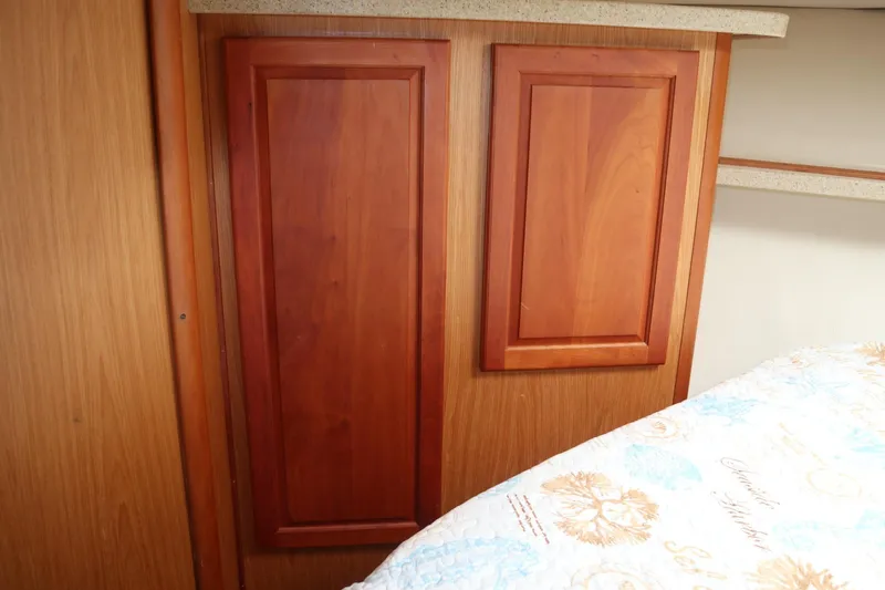  Yacht Photos Pics Interior of 2005 Luhrs 38 Convertible boat with wooden cabinetry and patterned bedding.