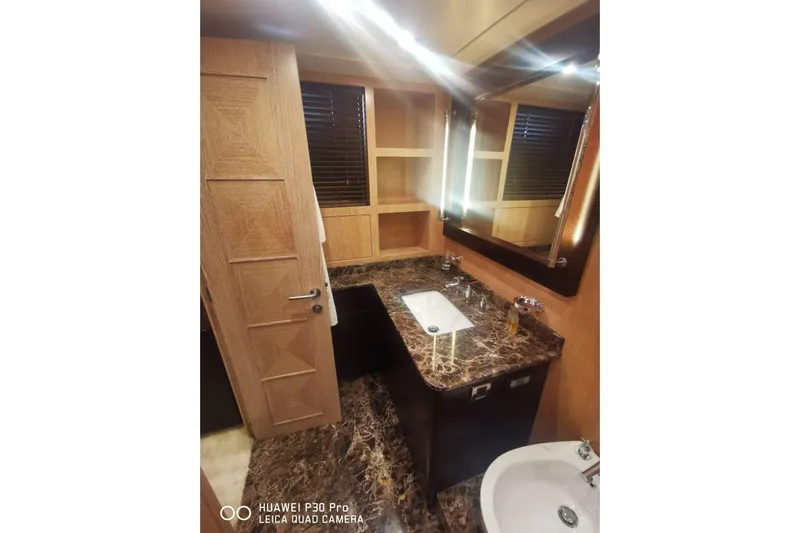  Yacht Photos Pics Luxurious bathroom in 2008 Mangusta 80 yacht with marble countertop and wooden accents.