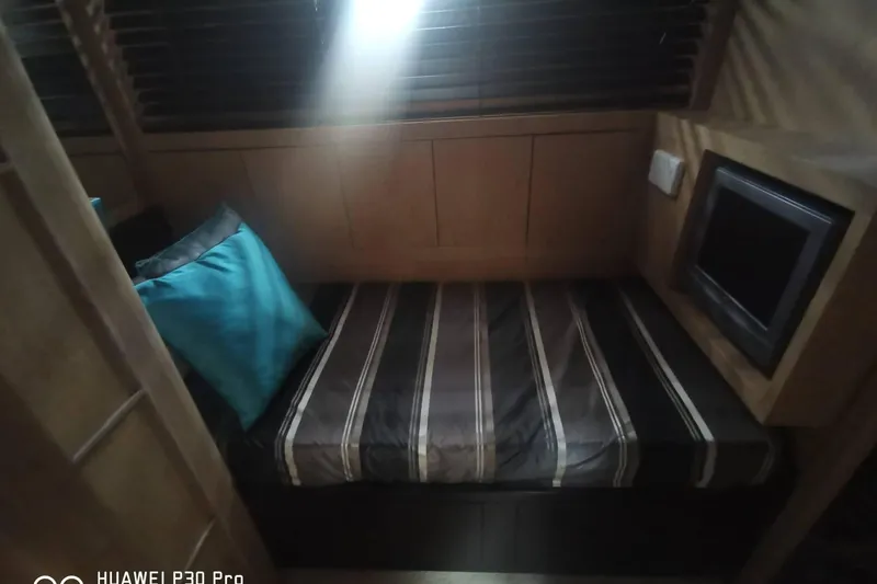  Yacht Photos Pics Cozy cabin interior of 2008 Mangusta 80 yacht with striped bedding and small TV.