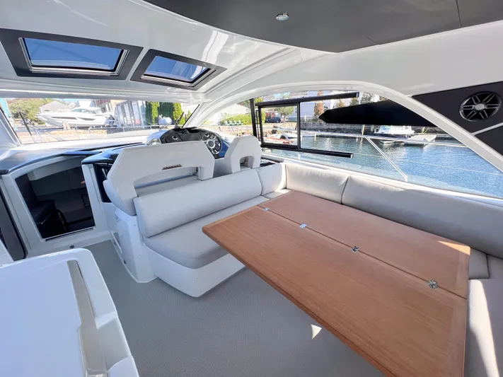 In Stock Yacht Photos Pics Interior of 2024 Beneteau Gran Turismo 45 yacht with modern seating and wooden table.