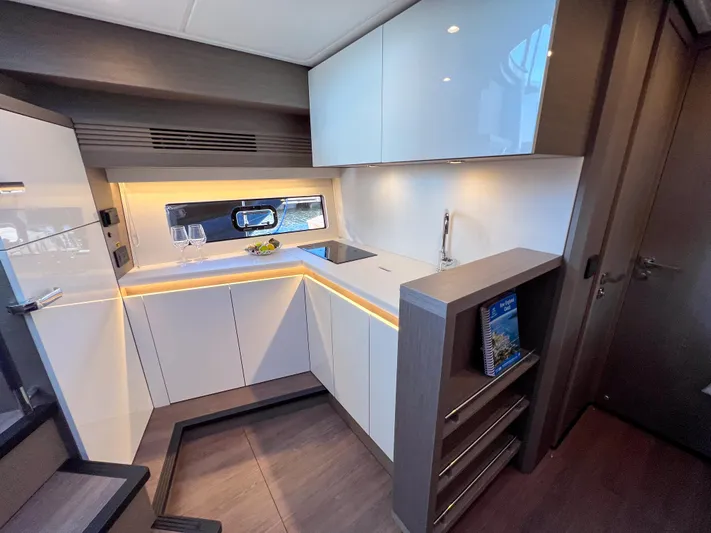 In Stock Yacht Photos Pics Modern kitchen interior of 2024 Beneteau Gran Turismo 45 yacht, featuring sleek cabinetry and ambient lighting.