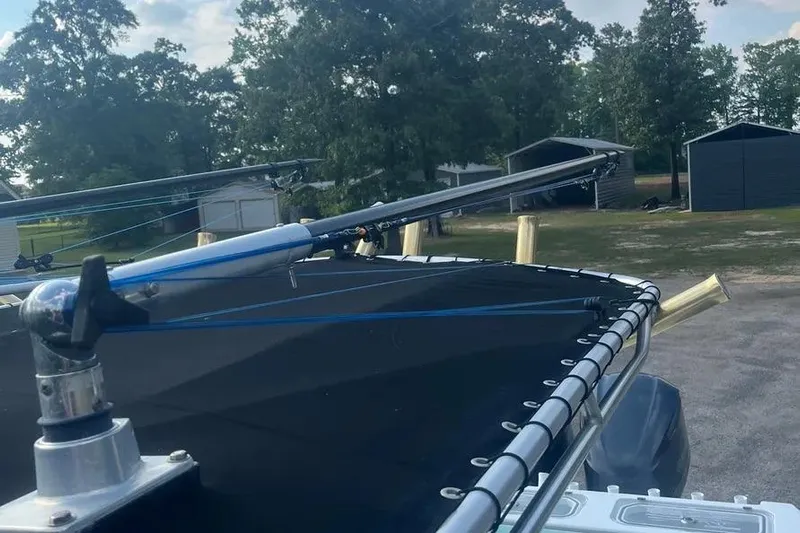  Yacht Photos Pics 2011 Contender 32 ST boat with fishing rods on deck, surrounded by trees and sheds.