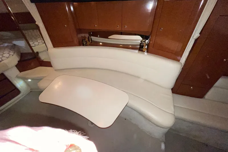  Yacht Photos Pics 2003 Sea Ray 340 Sundancer interior with curved seating and table, featuring wood cabinetry.