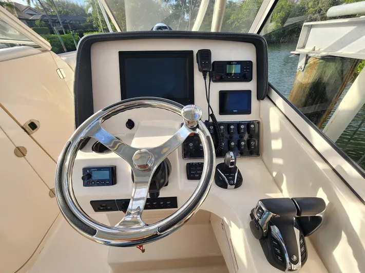  Yacht Photos Pics 2023 Grady-White Freedom 275 boat helm with steering wheel and control panel.