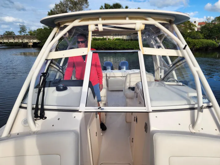  Yacht Photos Pics 2023 Grady-White Freedom 275 boat on water, person at helm, clear skies.