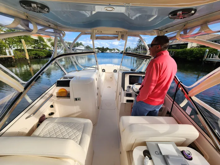  Yacht Photos Pics 2023 Grady-White Freedom 275 boat interior with person steering on a sunny day.