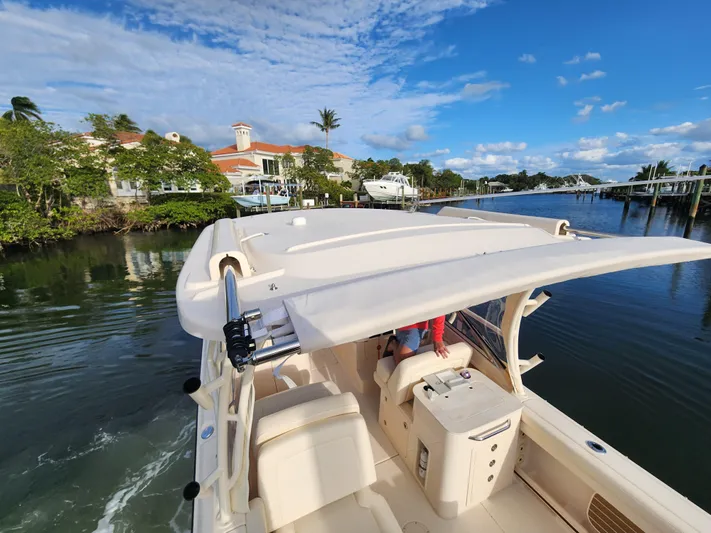  Yacht Photos Pics 2023 Grady-White Freedom 275 boat cruising on a scenic waterway near luxury homes.