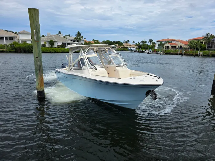  Yacht Photos Pics 2023 Grady-White Freedom 275 boat navigating a calm residential waterway.