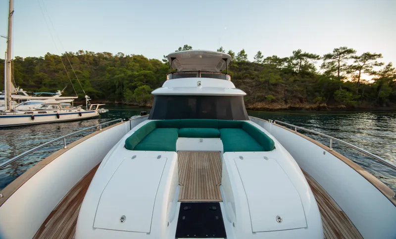  Yacht Photos Pics 2024 Azimut Magellano 66 yacht with green seating, docked near a forested shoreline.