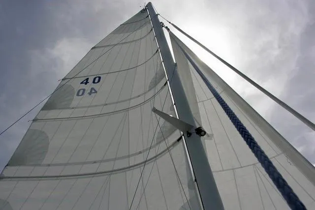 Wingnut Yacht Photos Pics Sailboat mast and sails of Hughes 40, 2012 model, against cloudy sky.