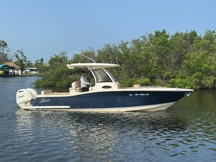  Yacht Photos Pics 2020 Scout 277 LXF boat cruising on a calm waterway with lush greenery.
