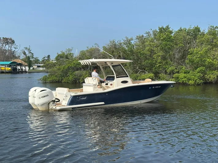  Yacht Photos Pics 2020 Scout 277 LXF boat cruising on a calm river with lush greenery.