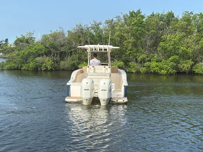  Yacht Photos Pics 2020 Scout 277 LXF boat navigating a calm waterway with lush greenery.