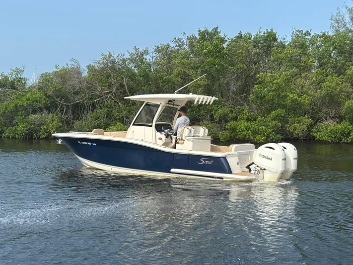  Yacht Photos Pics 2020 Scout 277 LXF boat cruising on a calm river with lush greenery.
