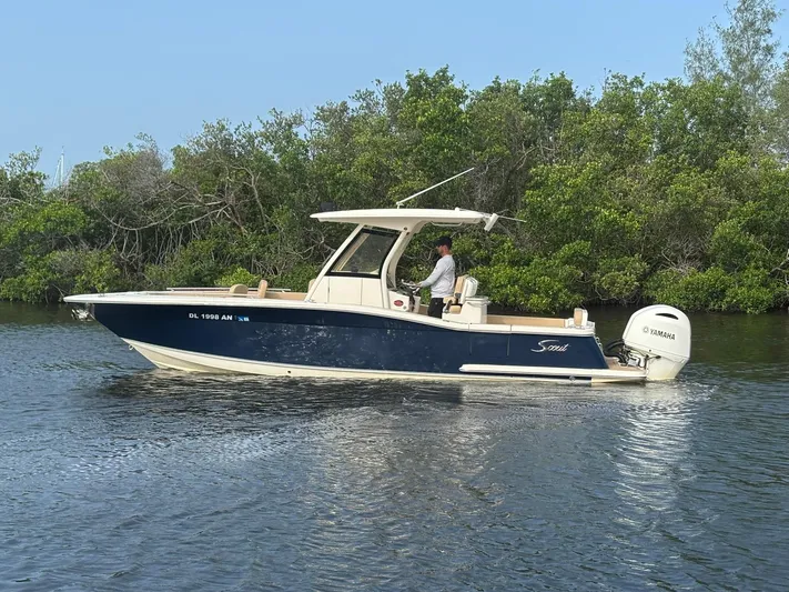  Yacht Photos Pics 2020 Scout 277 LXF boat cruising on a calm river with lush greenery.