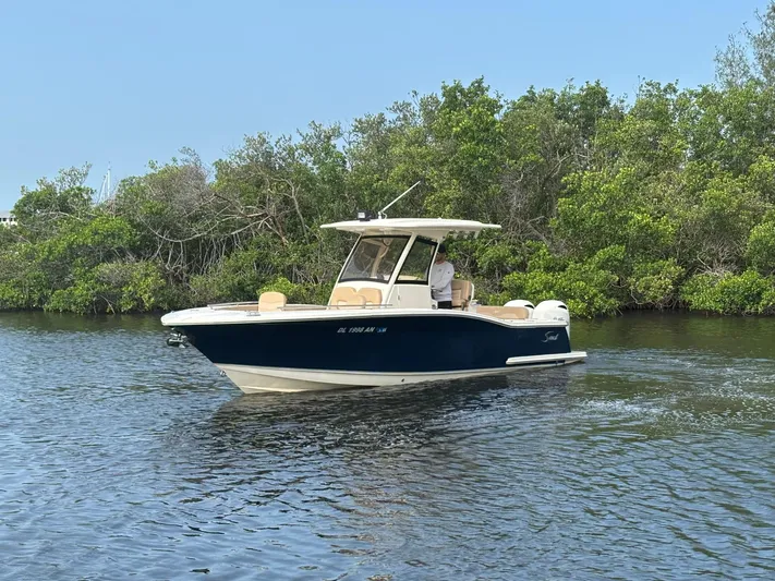  Yacht Photos Pics 2020 Scout 277 LXF boat cruising on a calm river near lush greenery.