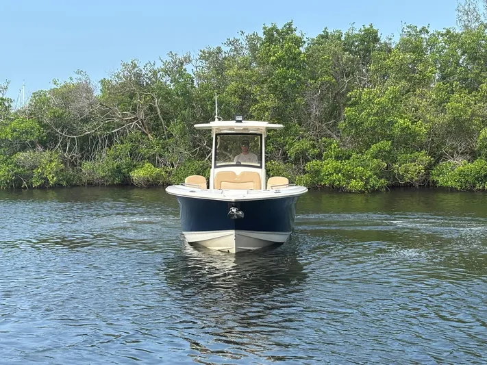  Yacht Photos Pics 2020 Scout 277 LXF boat cruising on a calm river with lush greenery.