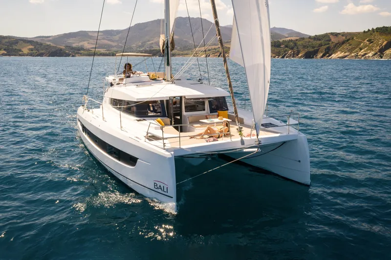  Yacht Photos Pics 2026 Bali 4.2 catamaran sailing on clear blue waters near scenic coastline.