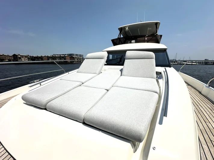 Perpetually Investing Yacht Photos Pics Luxury 2022 Prestige 520 yacht with sun loungers on deck, docked by waterfront.