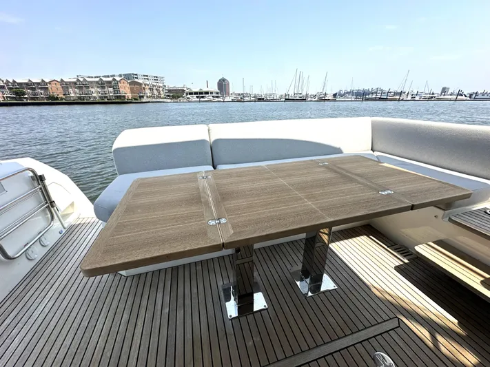 Perpetually Investing Yacht Photos Pics Prestige 520 yacht deck with wooden table, overlooking marina, 2022 model.