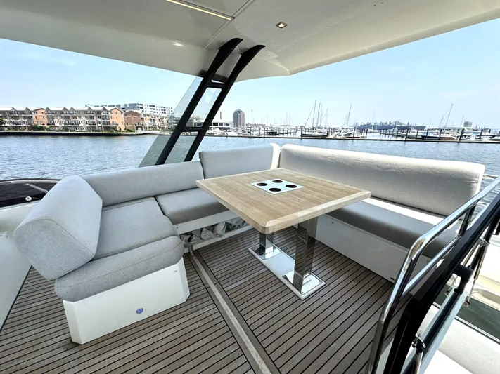 Perpetually Investing Yacht Photos Pics Luxurious 2022 Prestige 520 yacht deck with elegant seating and table, overlooking marina.