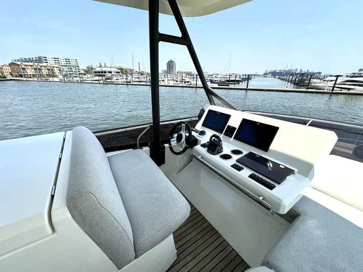 Perpetually Investing Yacht Photos Pics Helm of 2022 Prestige 520 yacht with modern controls, overlooking marina.