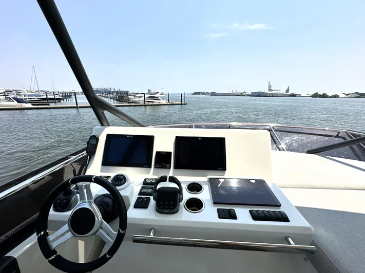 Perpetually Investing Yacht Photos Pics Helm of 2022 Prestige 520 yacht with modern controls, overlooking marina and water.