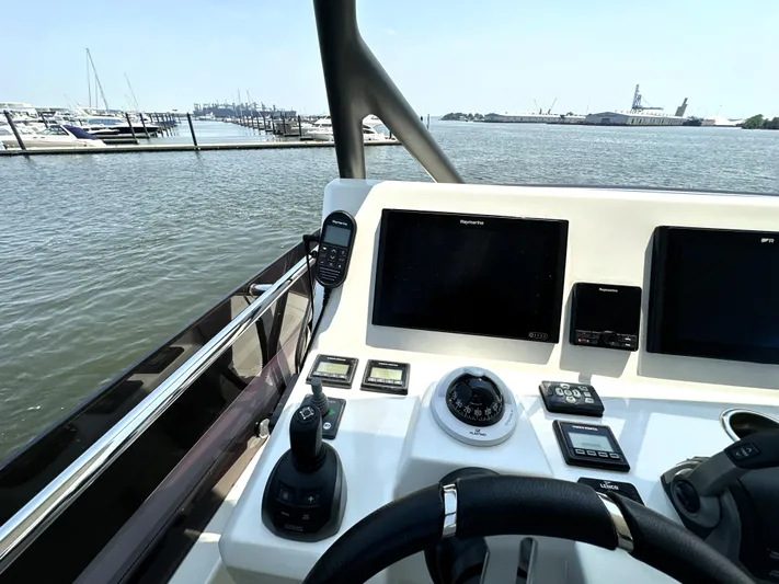 Perpetually Investing Yacht Photos Pics Helm of 2022 Prestige 520 yacht with navigation controls and waterfront view.