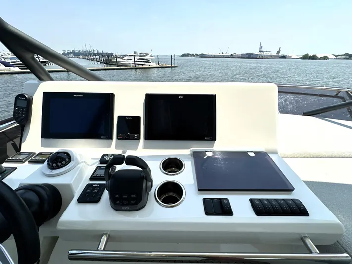 Perpetually Investing Yacht Photos Pics Helm of 2022 Prestige 520 yacht with navigation screens and controls, overlooking marina.