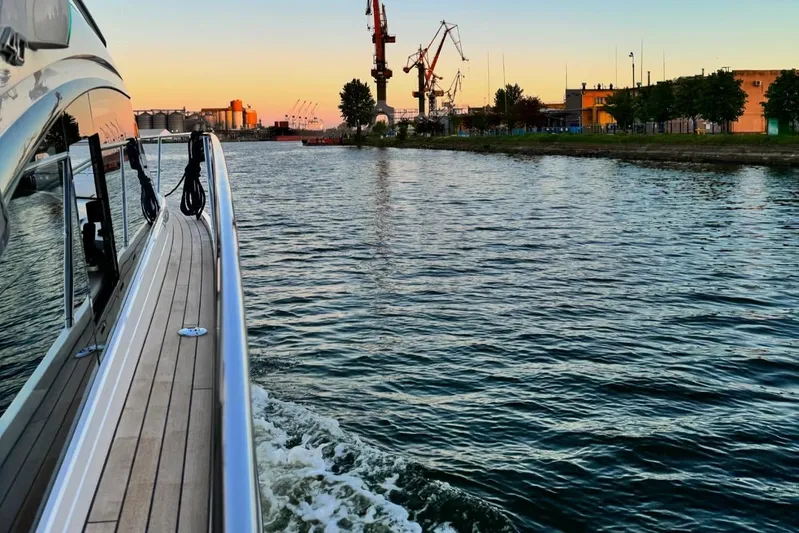 Rascal Yacht Photos Pics 2024 Princess V40 yacht cruising near industrial waterfront at sunset.